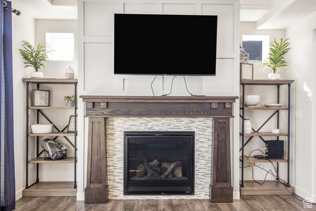 Room details with a tiled fireplace, baseboards, and wood finished floors