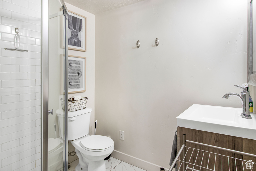 Bathroom featuring walk in shower, vanity, toilet, marble finish floor, and baseboards