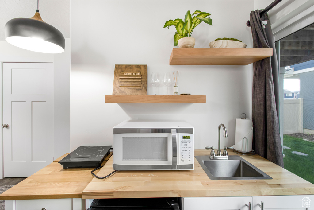 Interior space with a sink, open shelves, wood counters, and white microwave