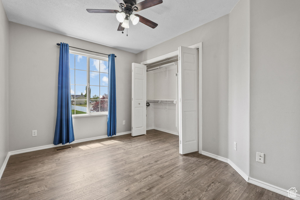 Unfurnished bedroom featuring a closet, visible vents, wood finished floors, and baseboards
