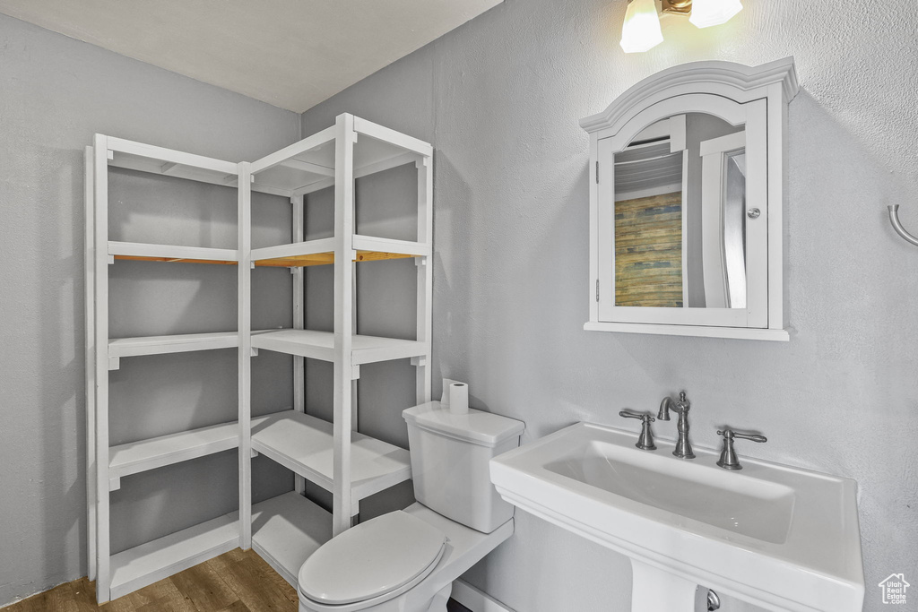 Bathroom with toilet, wood finished floors, and a sink