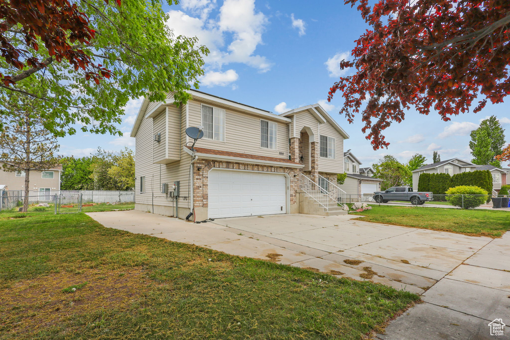 Traditional-style house with concrete driveway, an attached garage, fence, and a front yard