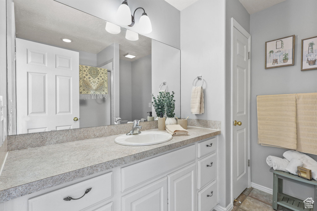 Bathroom featuring a shower with shower curtain, baseboards, and vanity