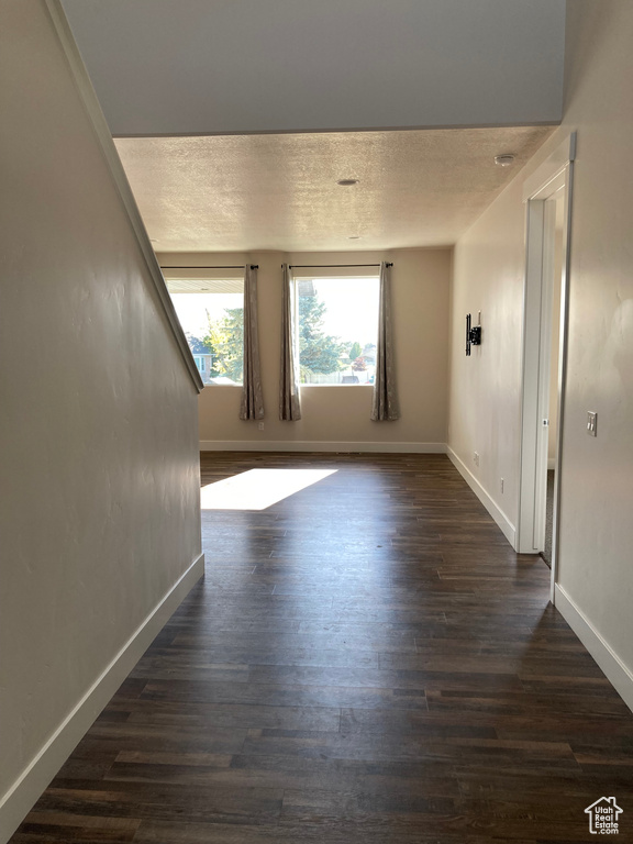 Empty room featuring dark wood finished floors and a textured ceiling