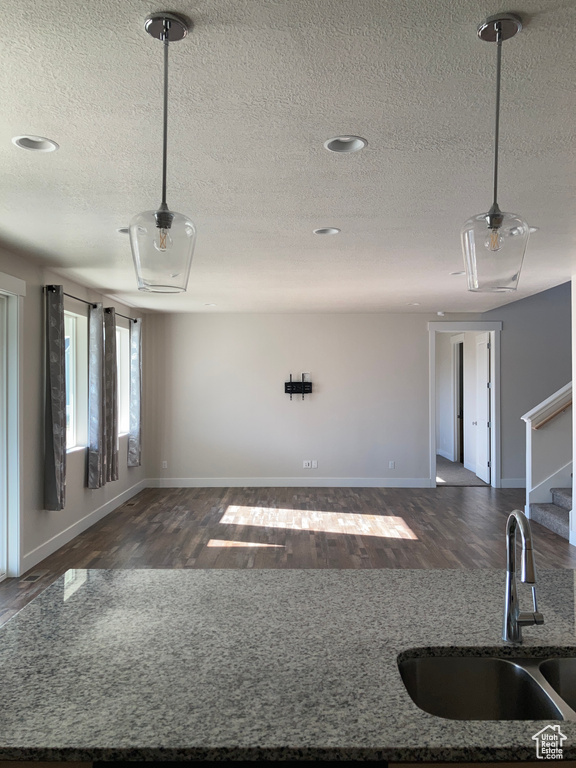 Unfurnished living room with dark wood-style flooring, a textured ceiling, and stairway
