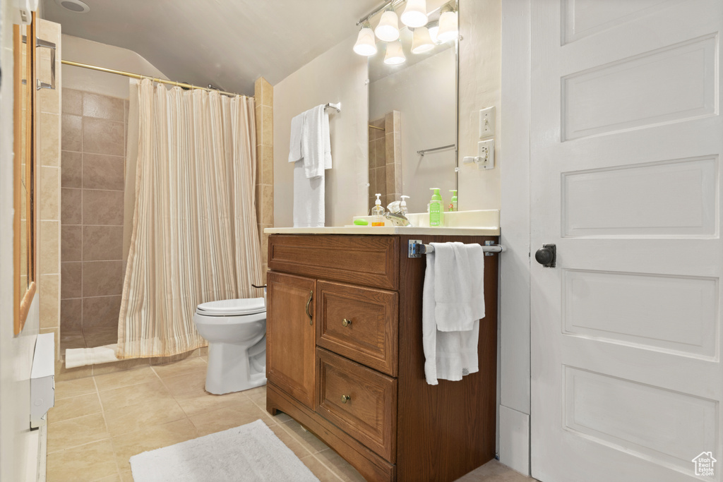 Bathroom featuring toilet, lofted ceiling, tile patterned floors, and a tile shower