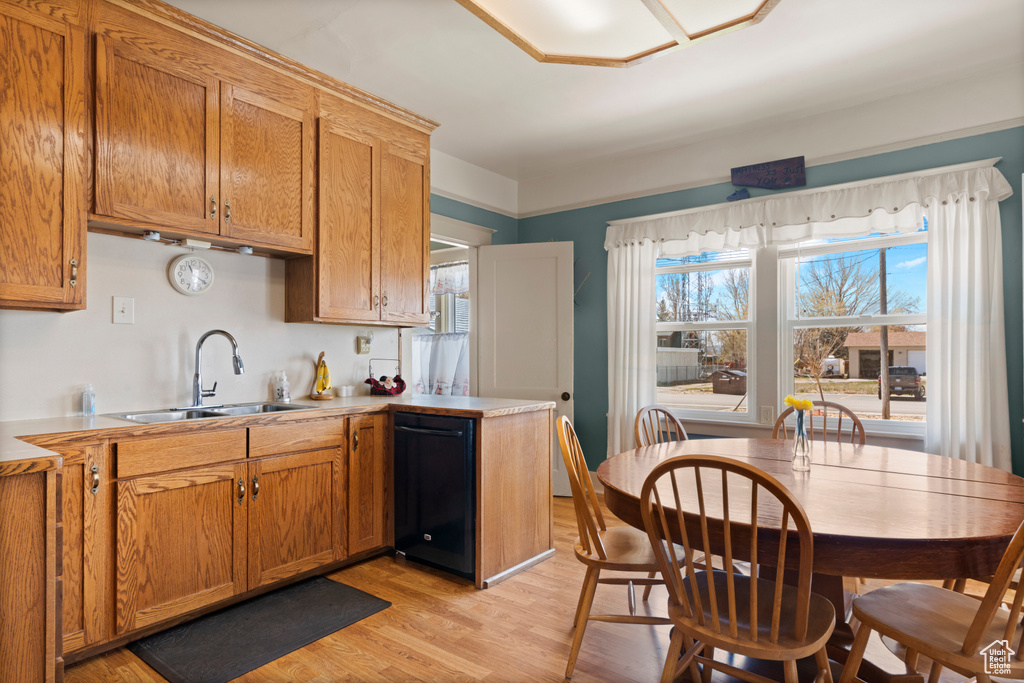 Kitchen with a sink, light countertops, light wood-type flooring, and dishwasher