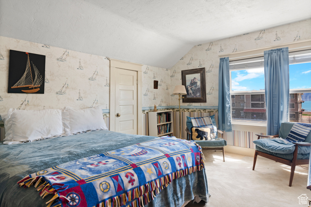 Bedroom featuring lofted ceiling, carpet, a textured ceiling, and wallpapered walls
