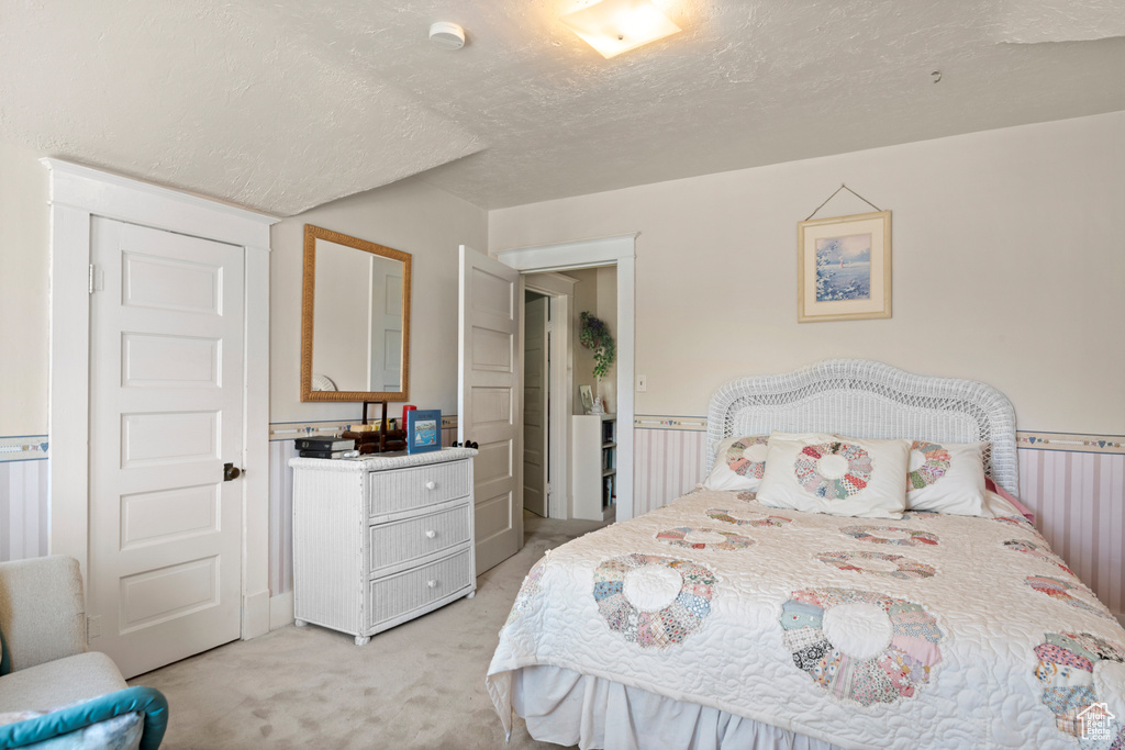 Bedroom featuring light carpet and a textured ceiling