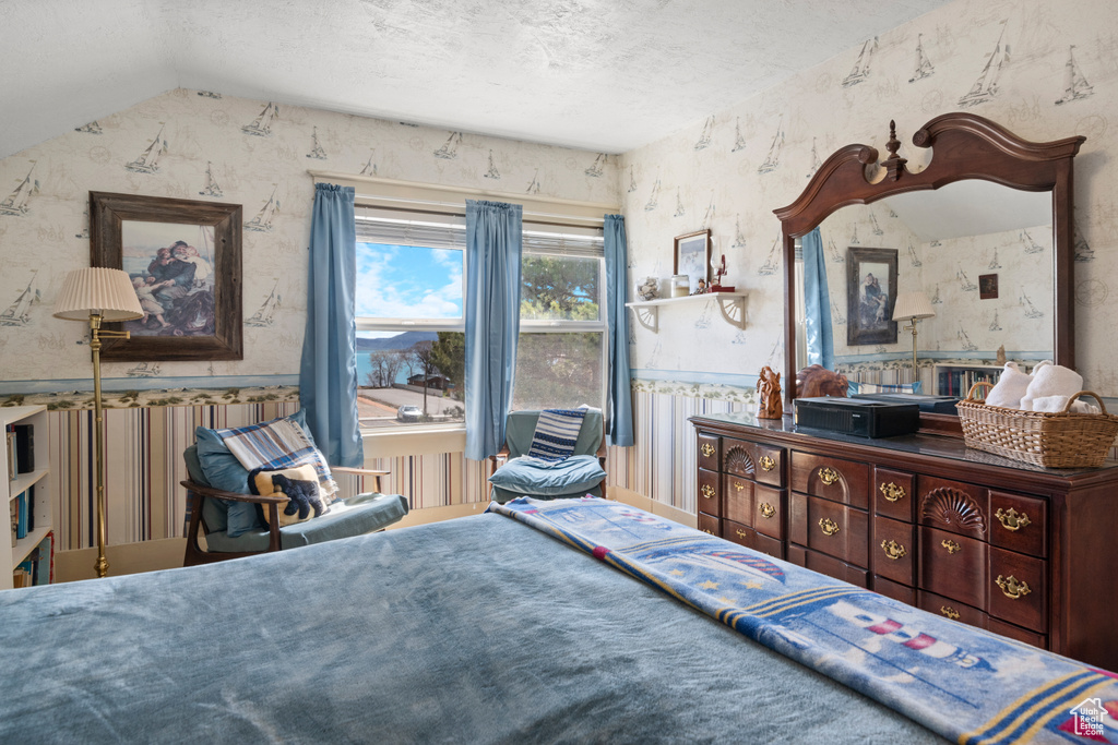 Bedroom with wallpapered walls and a textured ceiling