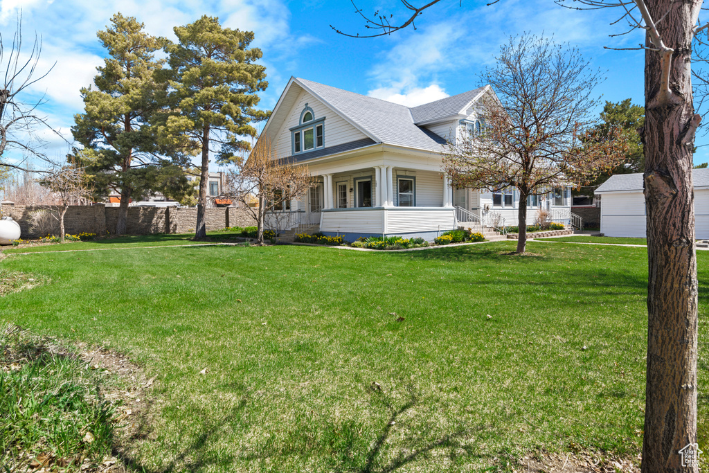 View of front of house featuring a porch, a shingled roof, and a front lawn