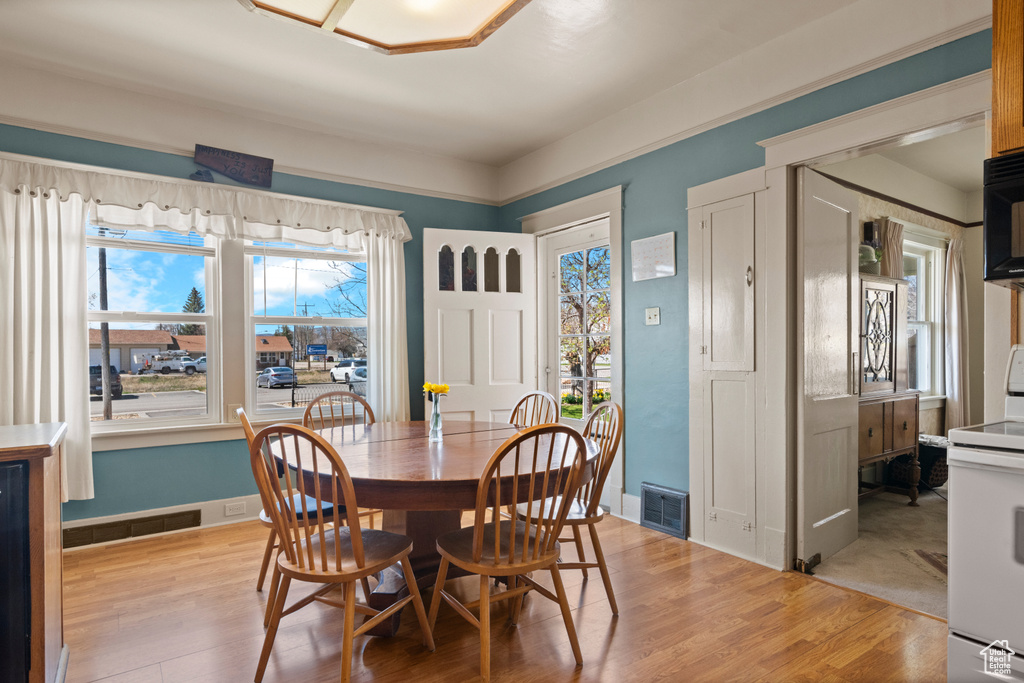 Dining area with baseboards, light wood-style floors, and visible vents
