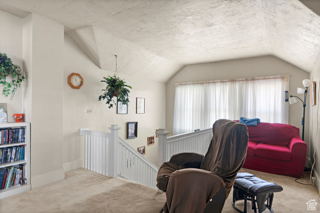 Living area featuring carpet, an upstairs landing, and lofted ceiling