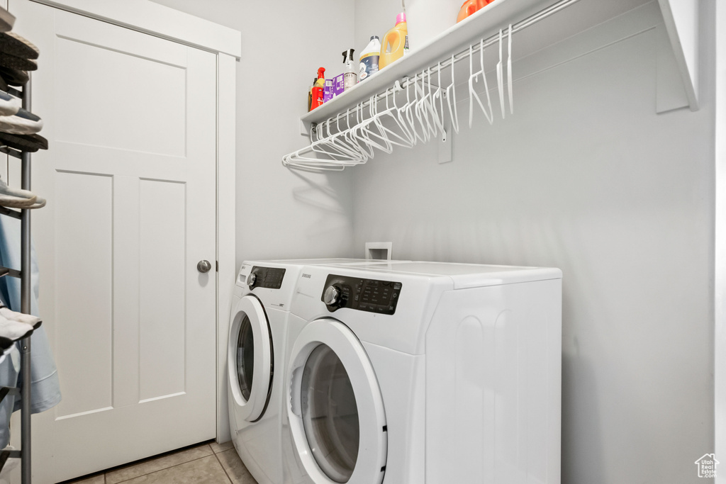 Washroom featuring washing machine and clothes dryer, laundry area, and light tile patterned floors
