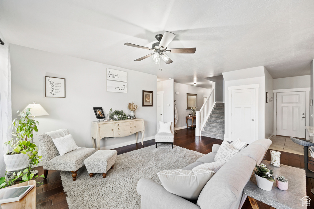 Living room with baseboards, stairway, wood finished floors, and a ceiling fan