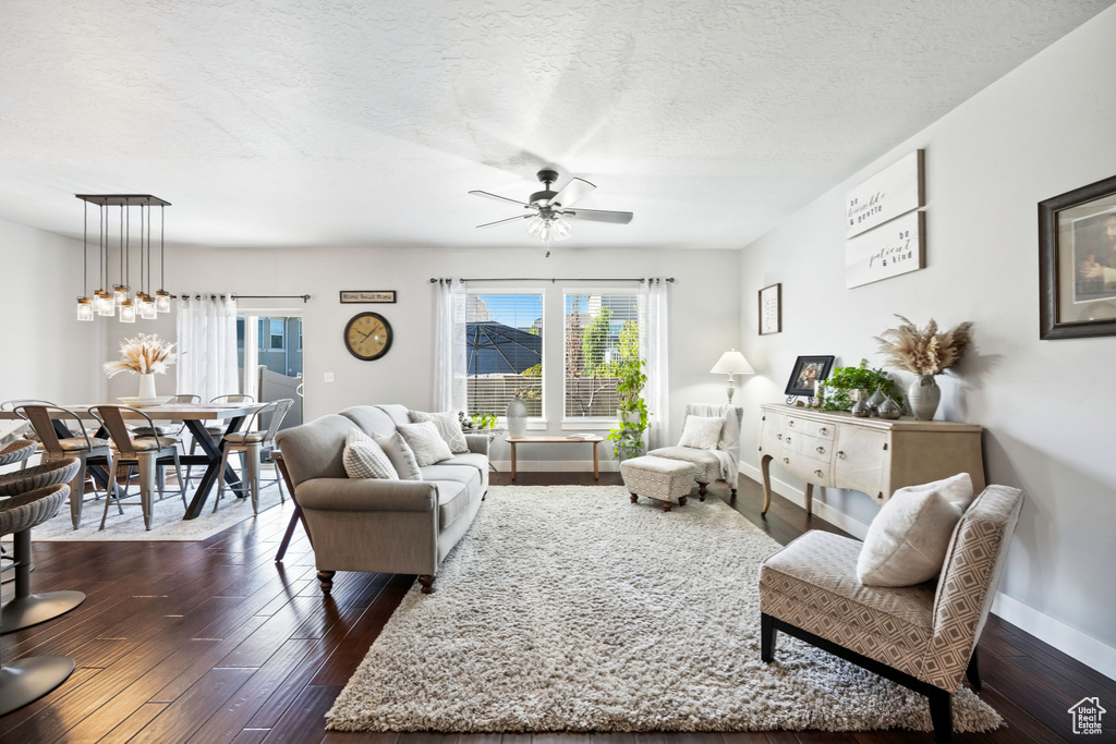 Living room with a ceiling fan, a wealth of natural light, baseboards, and dark wood finished floors