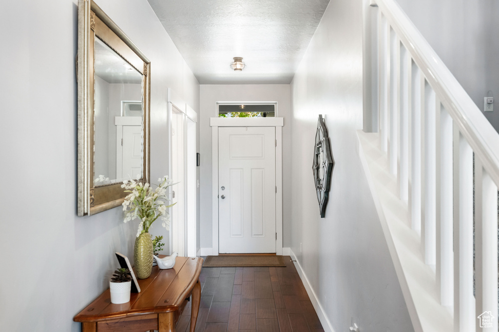 Entryway featuring dark wood finished floors, stairway, and baseboards