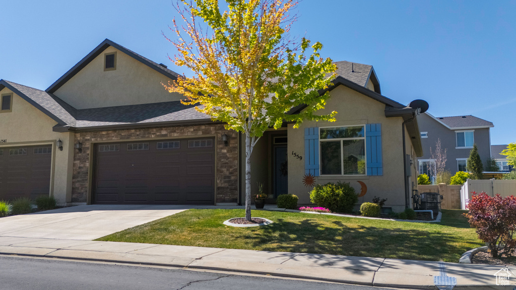 View of front of house with driveway, fence, a garage, stucco siding, and a front yard