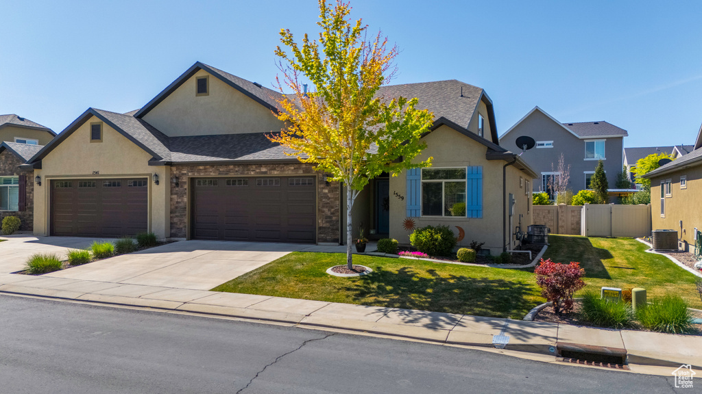 View of front of property featuring a front lawn, stucco siding, fence, and a garage