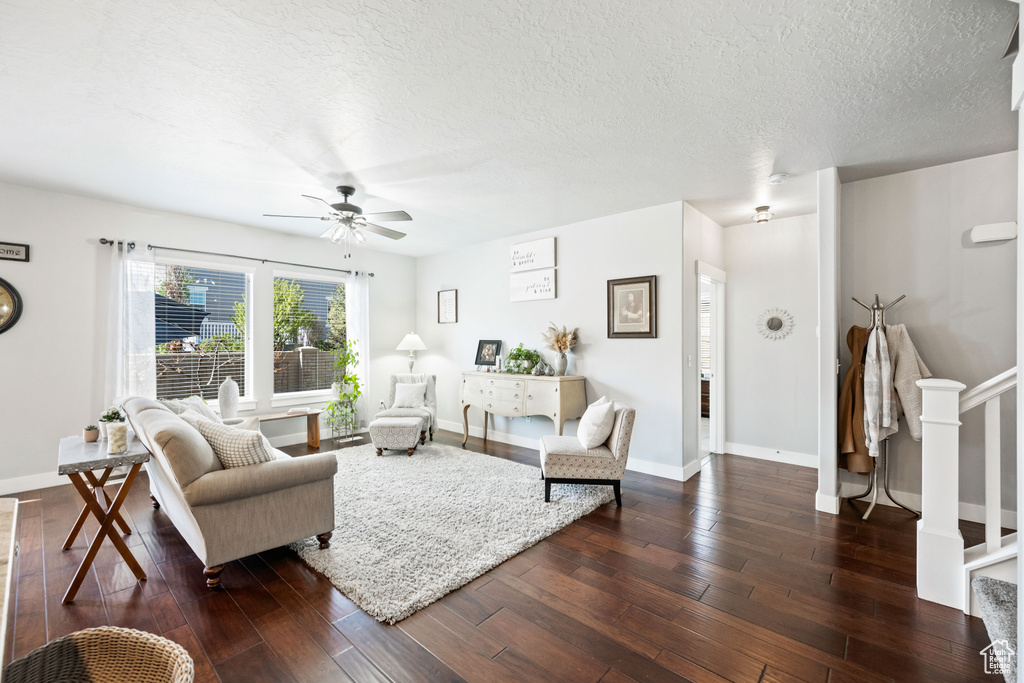 Living room with dark wood-type flooring, baseboards, and ceiling fan