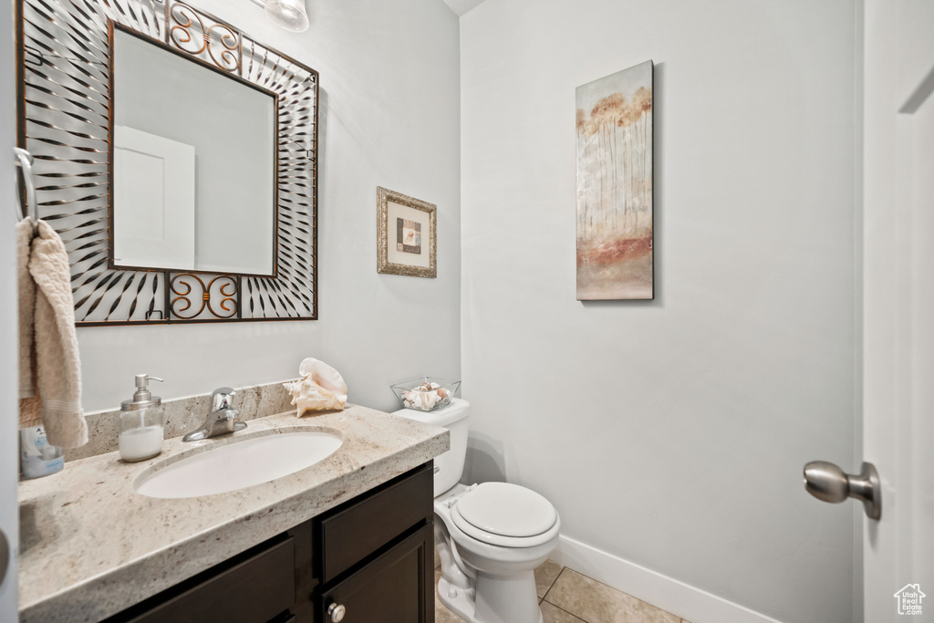 Half bathroom with tile patterned flooring, toilet, baseboards, and vanity