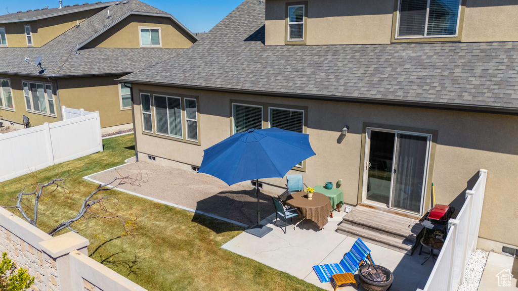 Back of house with a shingled roof, stucco siding, and a fire pit