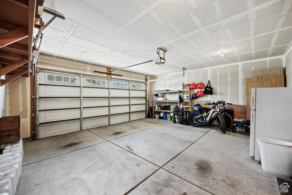 Garage featuring freestanding refrigerator and a garage door opener