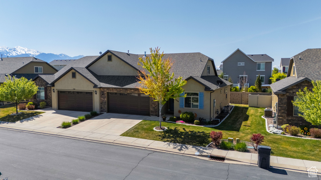 Traditional-style home featuring roof with shingles, fence, driveway, stucco siding, and a front lawn
