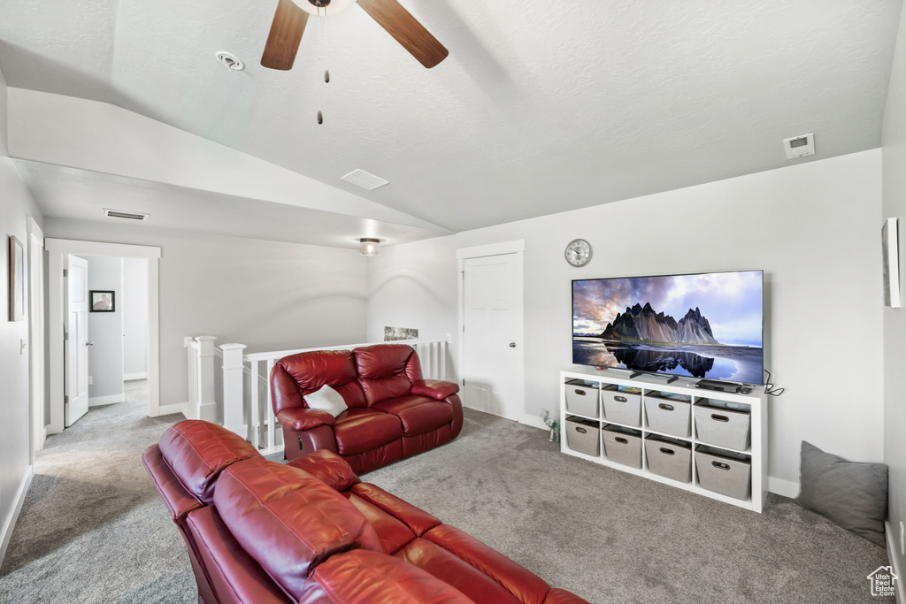 Living area featuring ceiling fan, visible vents, carpet, and vaulted ceiling