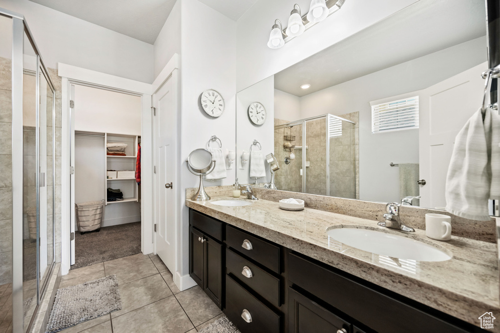 Full bath with a walk in closet, tile patterned floors, a stall shower, and a sink