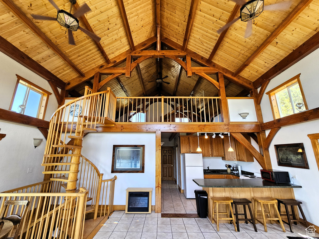 Kitchen featuring wood ceiling, high vaulted ceiling, freestanding refrigerator, dark countertops, and ceiling fan