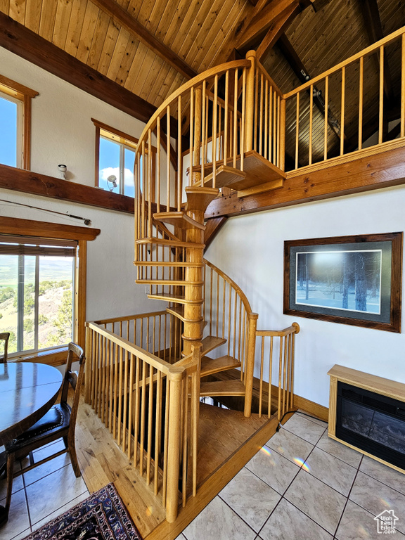 Stairs with wooden ceiling, tile patterned flooring, baseboards, and vaulted ceiling with beams