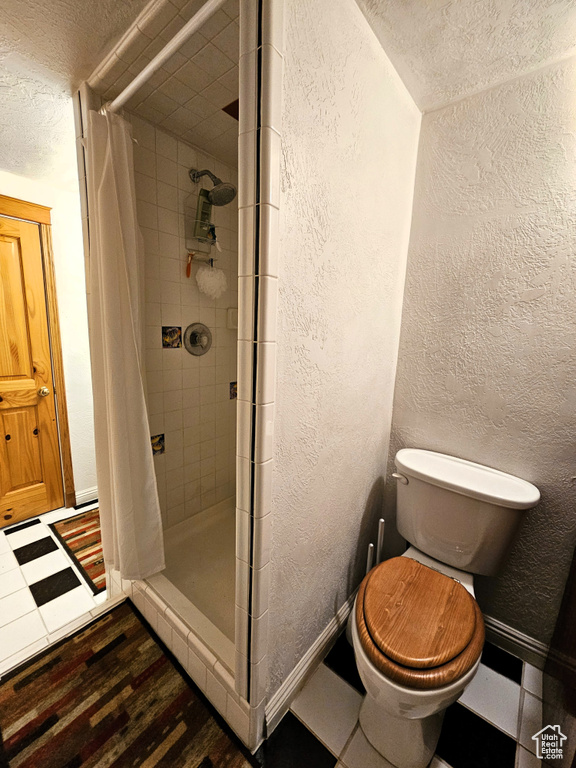 Full bath featuring a stall shower, toilet, a textured wall, and wood finished floors