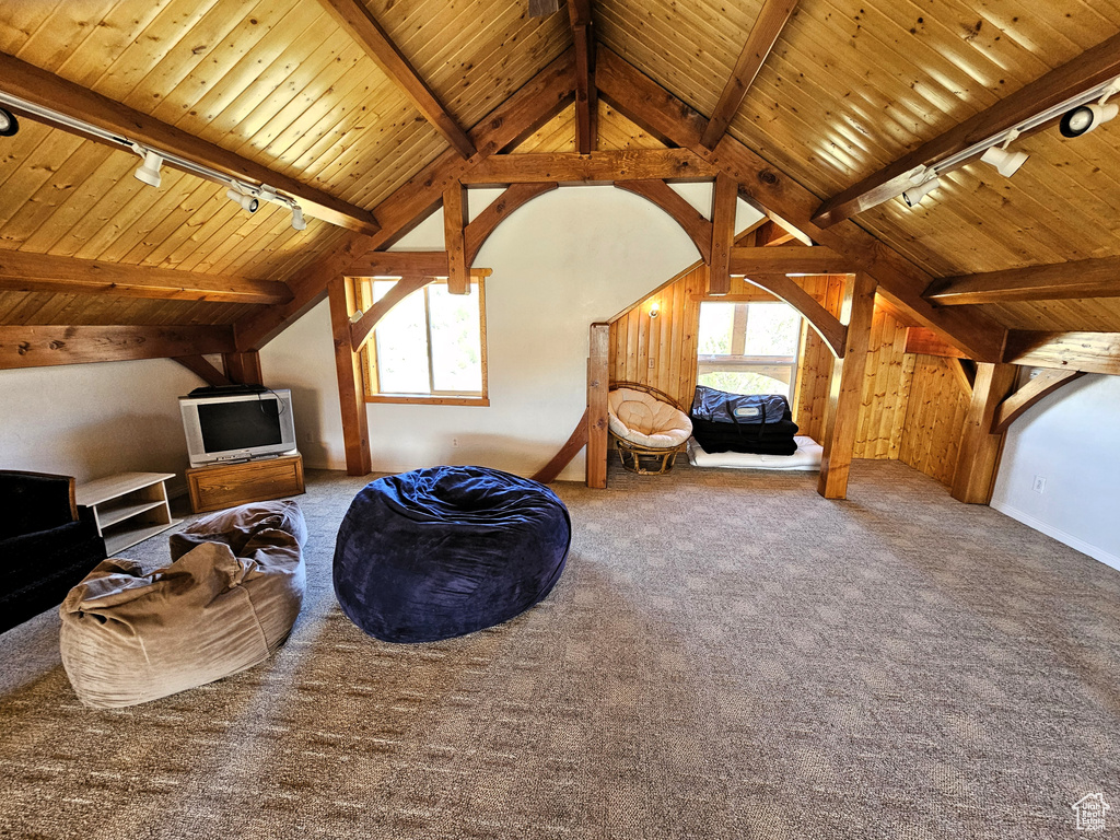 Interior space featuring rail lighting, wood ceiling, wood walls, and lofted ceiling with beams