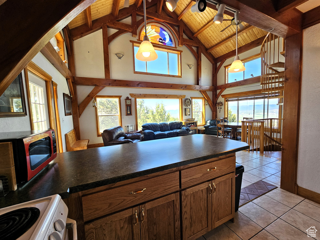 Kitchen featuring light tile patterned floors, dark countertops, a healthy amount of sunlight, and range