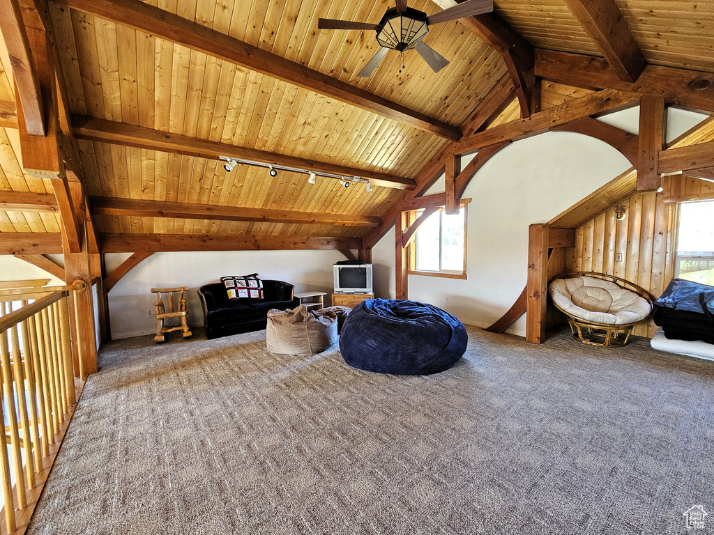 Interior space featuring carpet flooring, a healthy amount of sunlight, and vaulted ceiling with beams