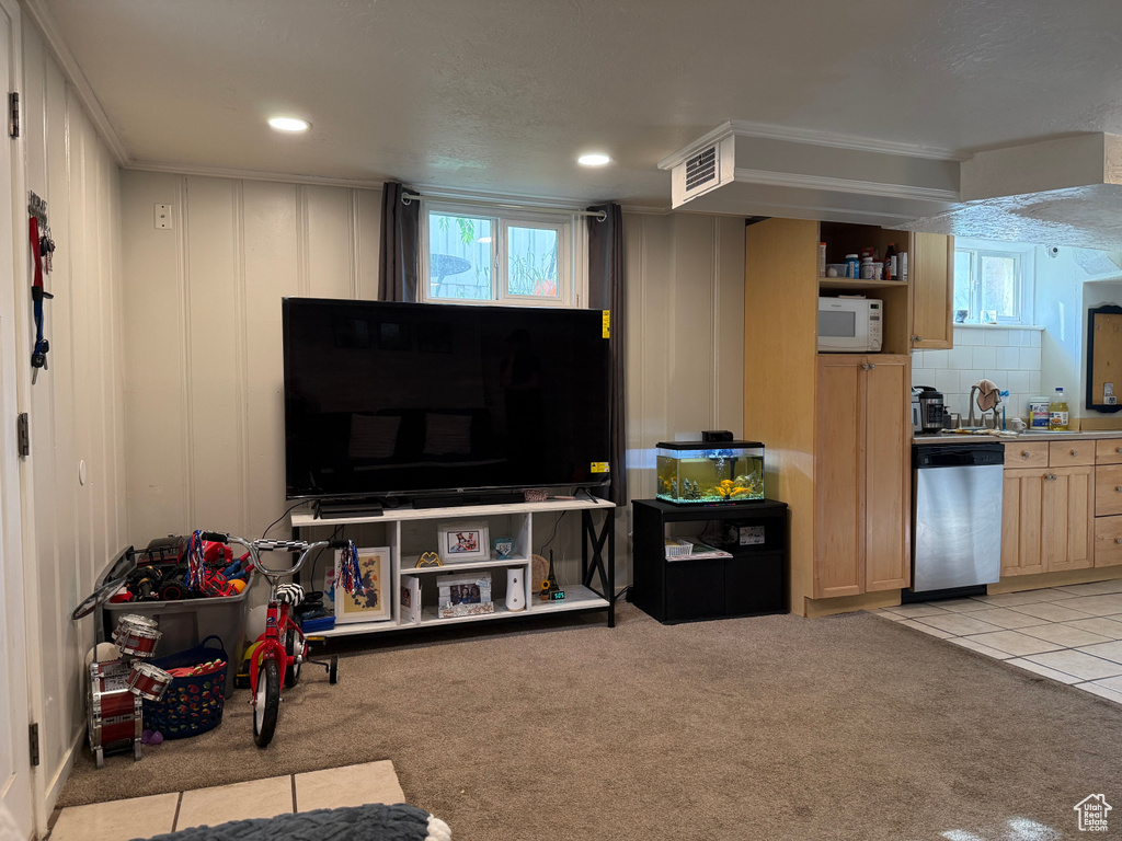 Living area featuring light colored carpet, a wealth of natural light, visible vents, and ornamental molding