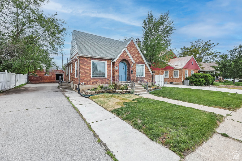 Tudor home with brick siding, a shingled roof, asphalt driveway, and cooling unit