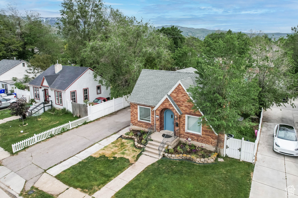View of front of property featuring a gate, brick siding, driveway, and roof with shingles