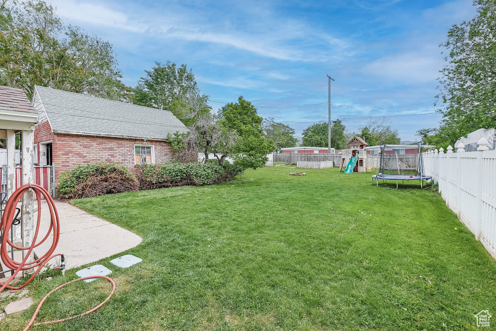 View of yard featuring a playground and a trampoline