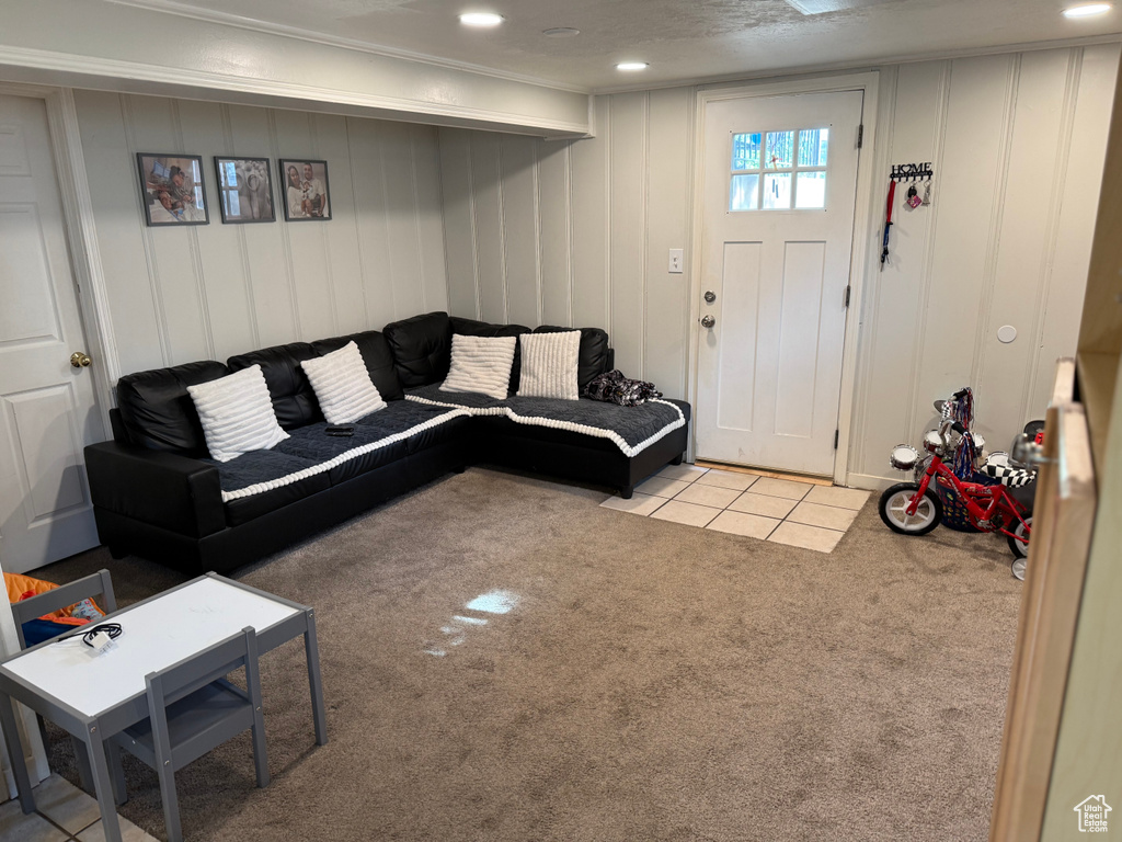 Carpeted living area featuring a decorative wall and tile patterned flooring