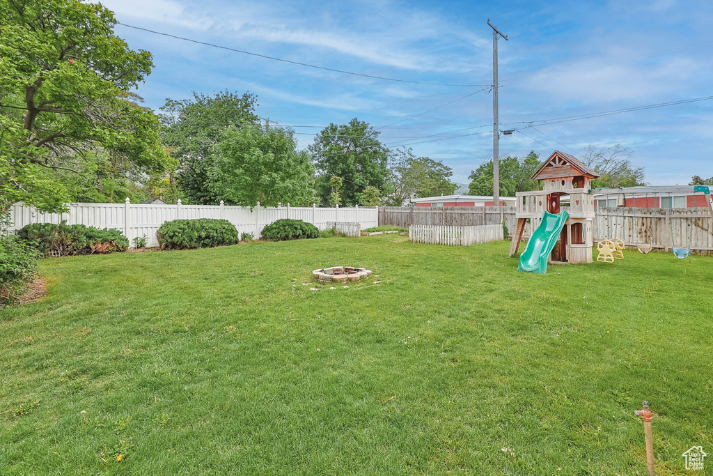 View of yard featuring a playground and an outdoor fire pit