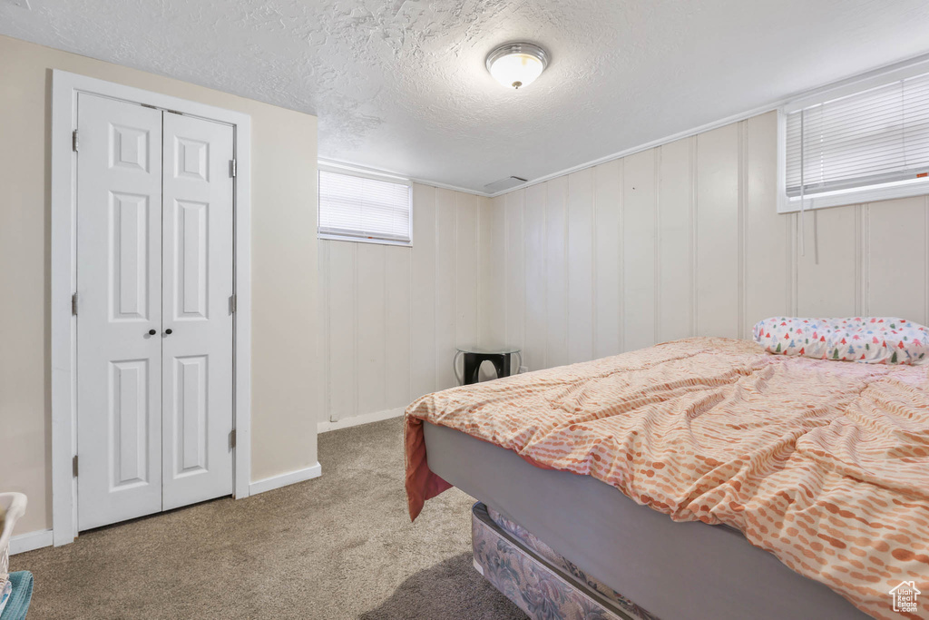Bedroom with carpet, a textured ceiling, a closet, and baseboards