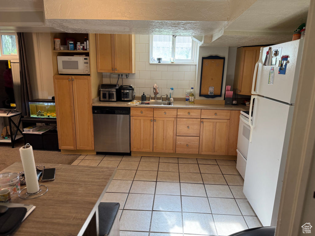 Kitchen featuring a sink, a textured ceiling, white appliances, light countertops, and light tile patterned flooring