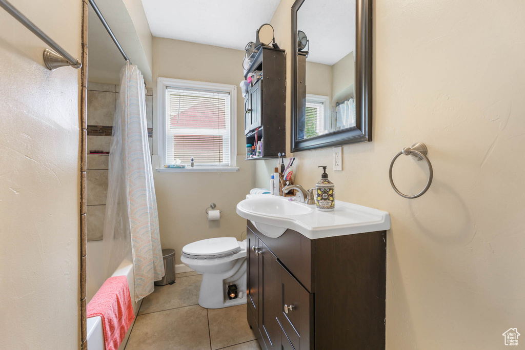 Bathroom with toilet, vanity, tile patterned floors, and shower / tub combo