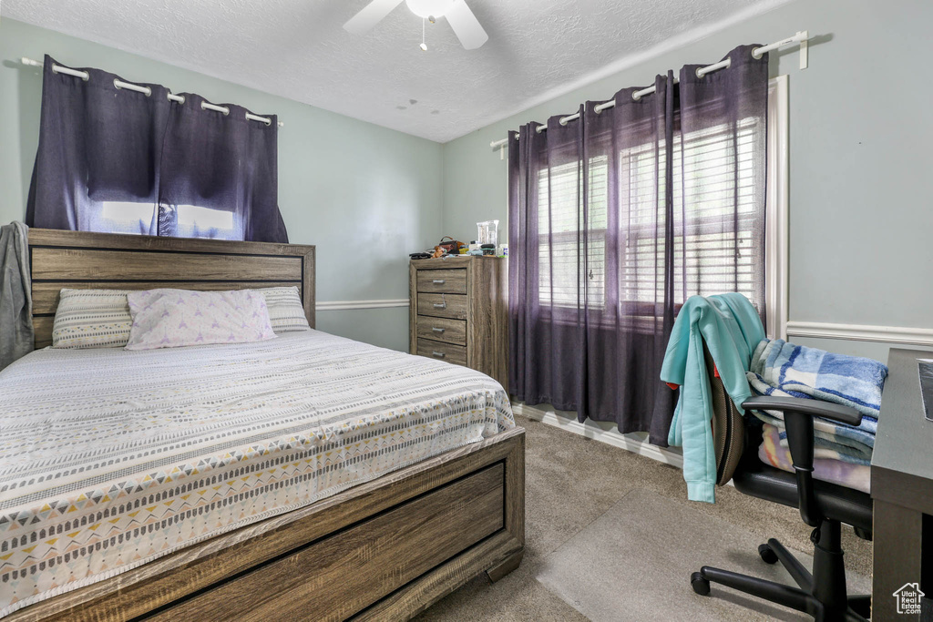 Carpeted bedroom featuring a textured ceiling and a ceiling fan