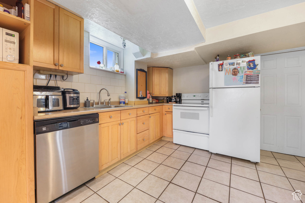 Kitchen featuring appliances with stainless steel finishes, a sink, light countertops, open shelves, and light tile patterned floors