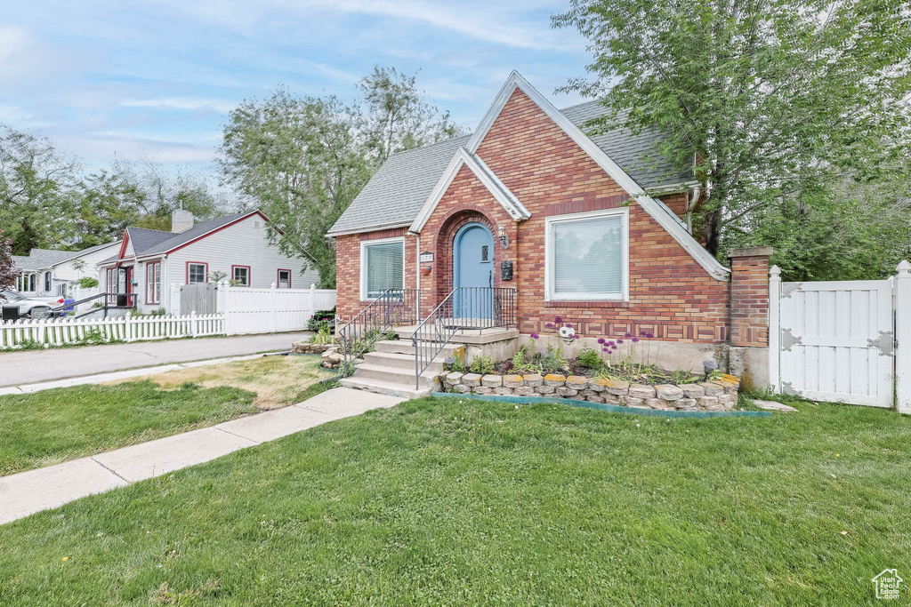 View of front of property with brick siding, a shingled roof, and a gate
