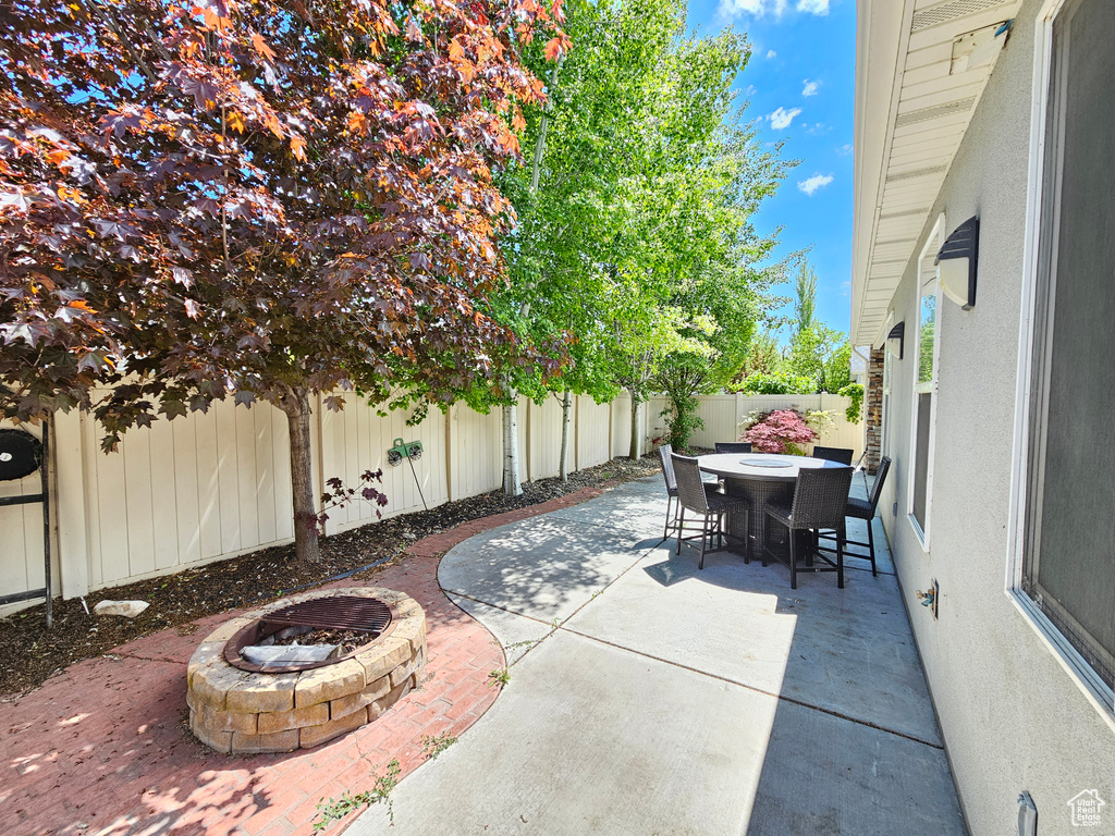 View of patio featuring outdoor dining space, a fenced backyard, and an outdoor fire pit