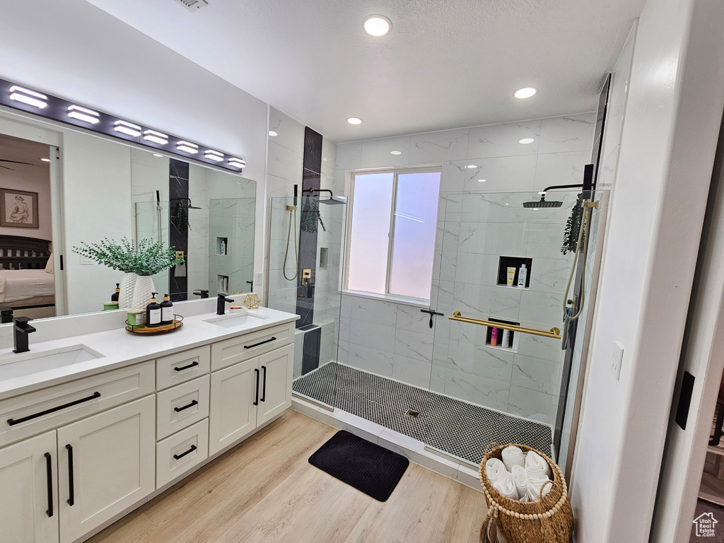 Bathroom featuring a sink, a stall shower, ensuite bath, and wood finished floors